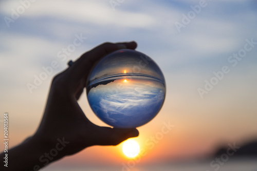 Travel vacation concept. Beautiful girl hanging crystal ball during sunset on beach. Summer creative photography