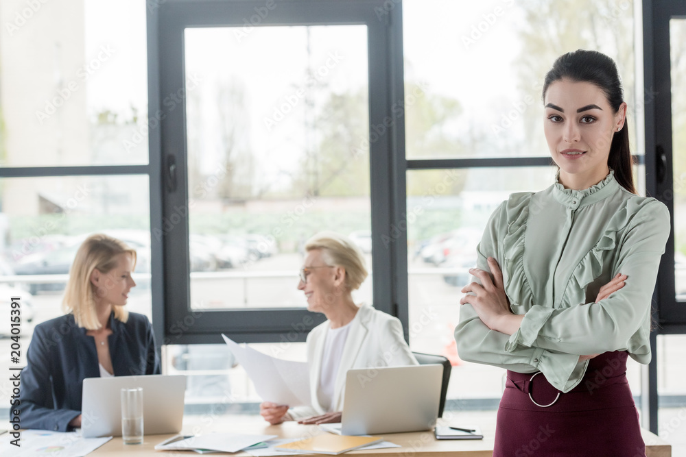 attractive young businesswoman standing with crossed arms at meeting in office attractive young businesswoman standing with crossed arms at meeting in office