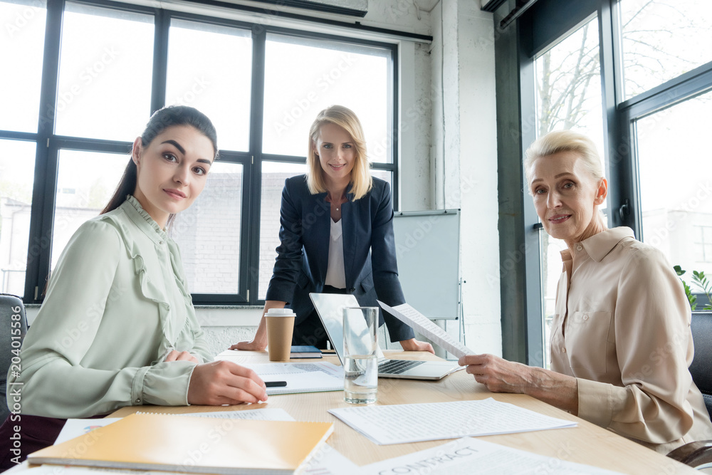 Obraz premium beautiful businesswomen looking at camera at meeting in office