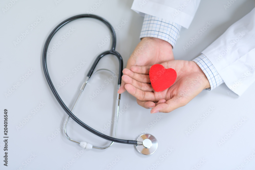 Male Doctor with stethoscope hand holding red heart shape in the hospital. Healthcare and Healthy Insurance concepts Male Doctor with stethoscope hand holding red heart shape in the hospital. Healthcare and Healthy Insurance concepts