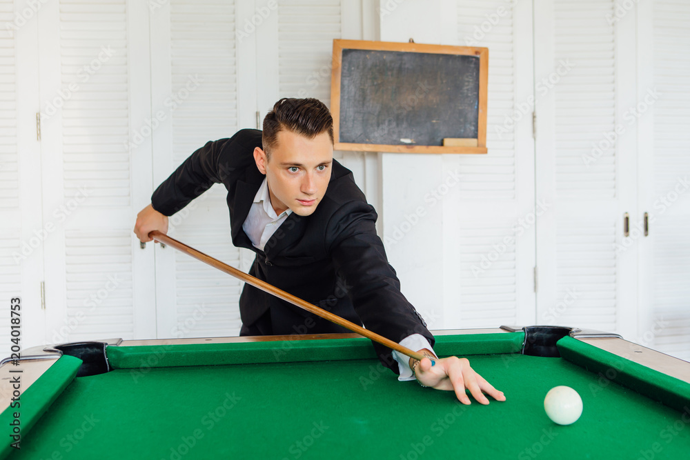 Fototapeta premium Young handsome man playing billiard game alone