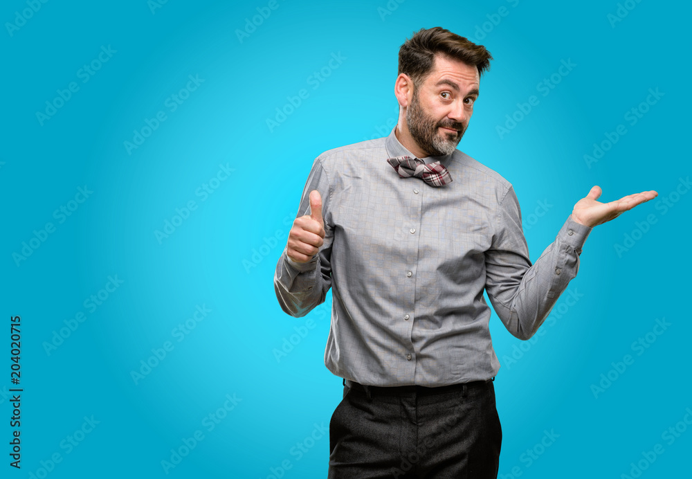 Middle age man, with beard and bow tie thumb up holding something in empty hand and making ok gesture Middle age man, with beard and bow tie thumb up holding something in empty hand and making ok gesture