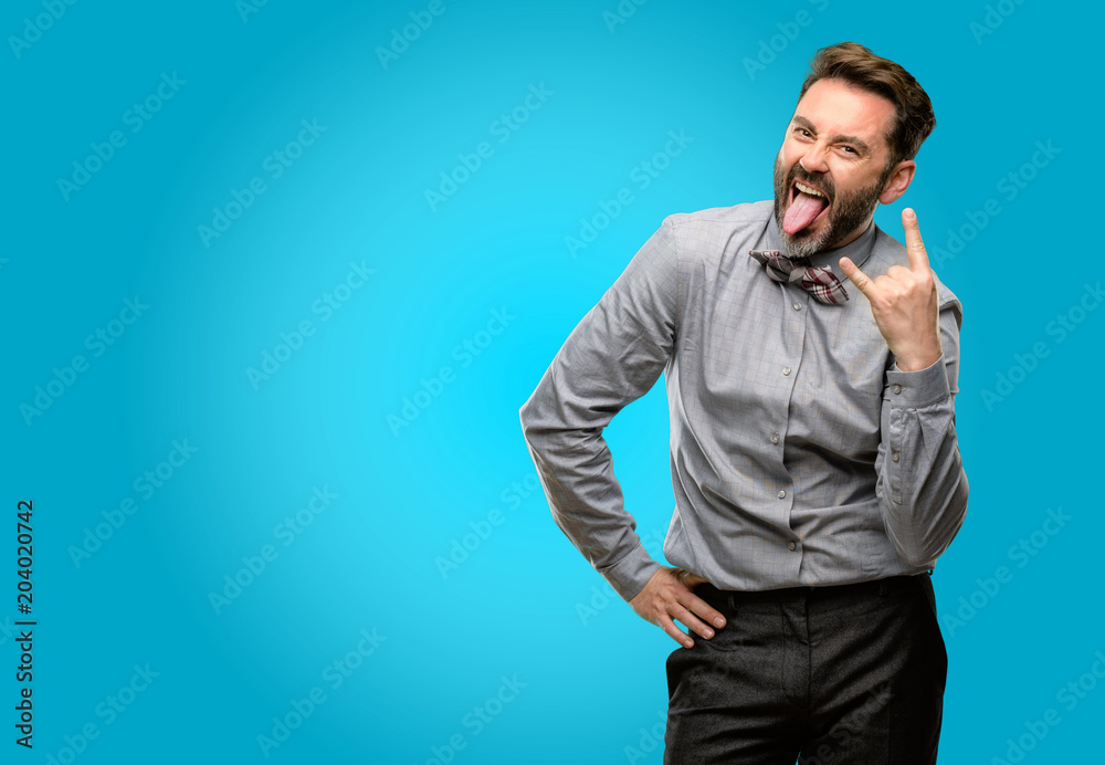 Middle age man, with beard and bow tie making rock symbol with hands, shouting and celebrating with tongue out Middle age man, with beard and bow tie making rock symbol with hands, shouting and celebrating with tongue out
