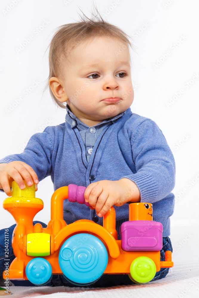 Little baby boy playing with plastic locomotive toy, child development concept Little baby boy playing with plastic locomotive toy, child development concept