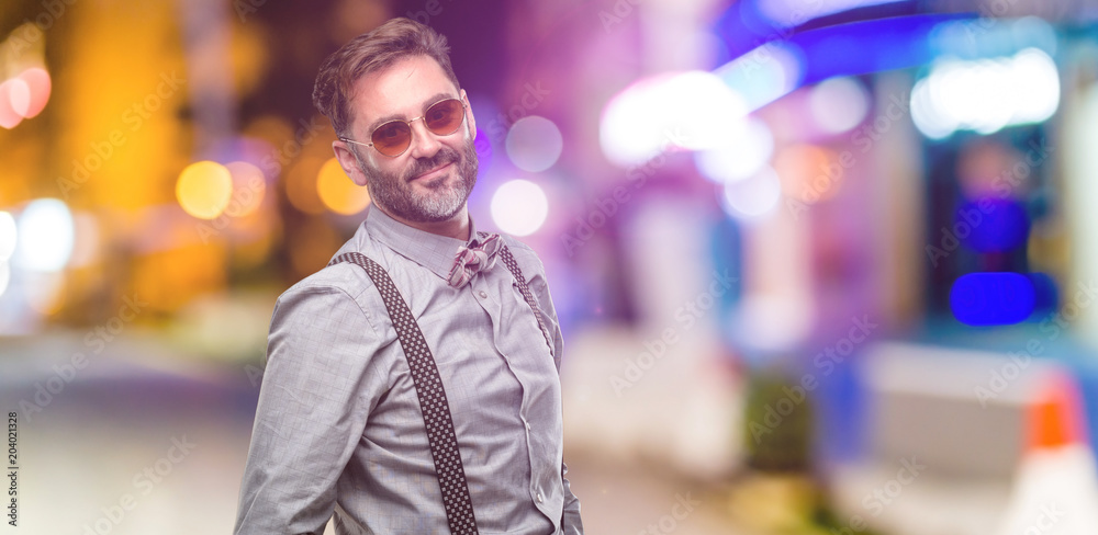 Middle age man, with beard and bow tie confident and happy with a big natural smile looking at camera at night club