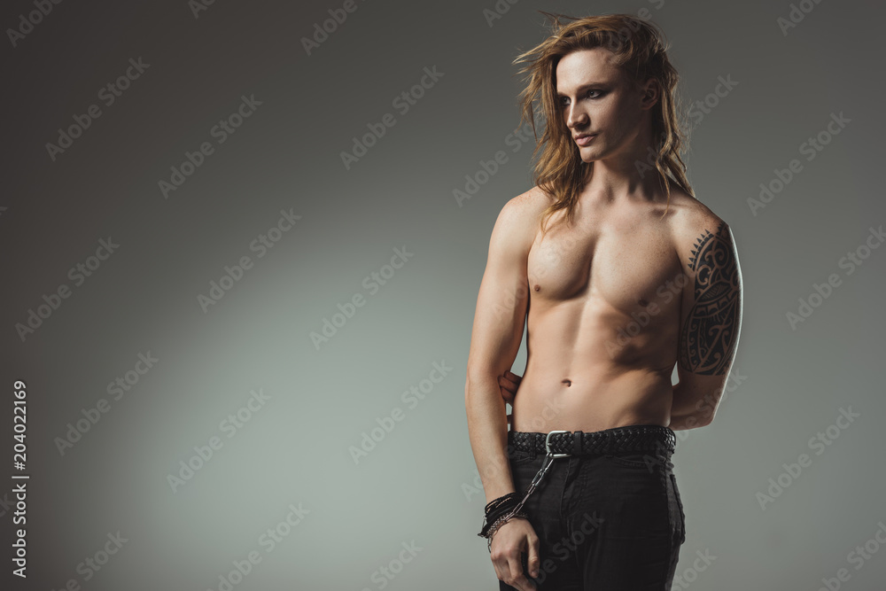 handsome shirtless man with tattoo posing in black jeans, isolated on grey