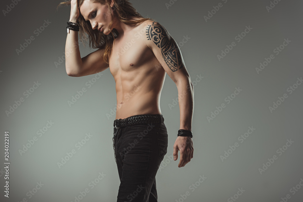 stylish shirtless man with tattoo posing in black jeans, isolated on grey