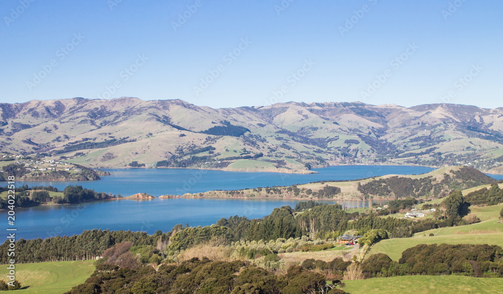 Landscape view of the rolling hills and harbour of Akaroa, Banks Peninsular, New Zealand.