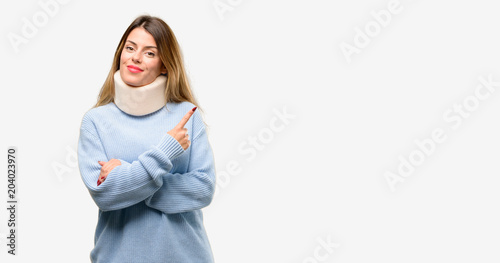 Young injured woman wearing neck brace collar pointing away side with finger photo