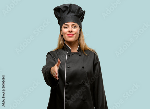 Young cook woman holds hands welcoming in handshake pose, expressing trust and success concept, greeting