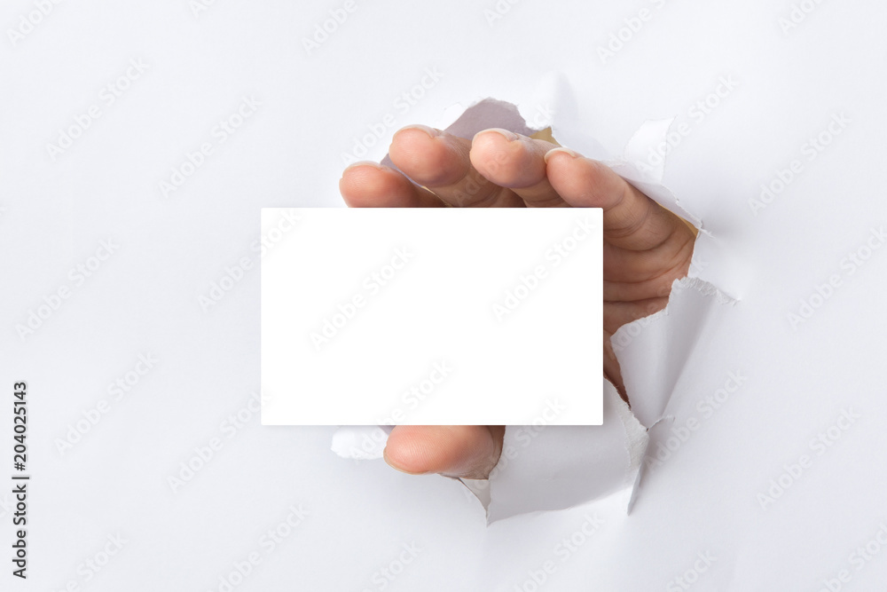 Fototapeta premium Hand holds white card through white torn paper background