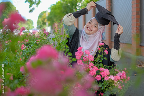 Beautiful female Muslim wearing a convocation robe and posed in happiness style after graduated in University of Canterbury. photo