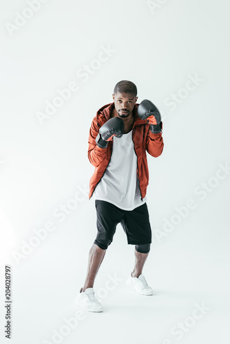 athletic african american boxer training in boxing gloves, isolated on white