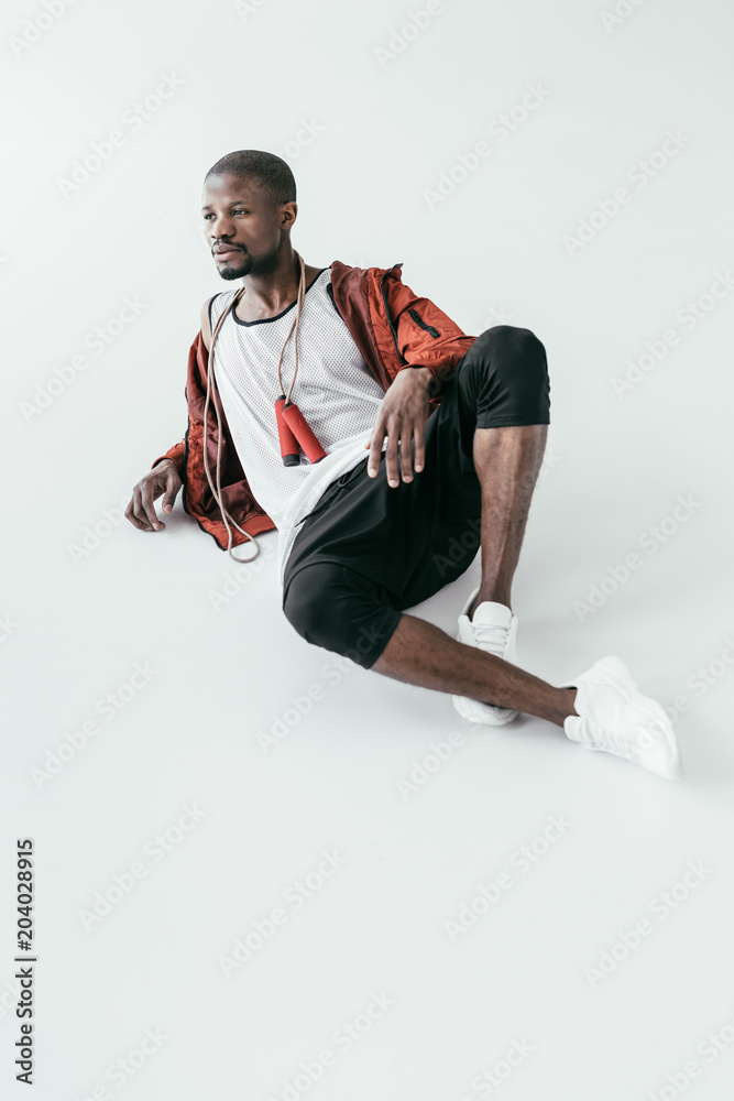 african american sportsman lying with skipping rope, isolated on white