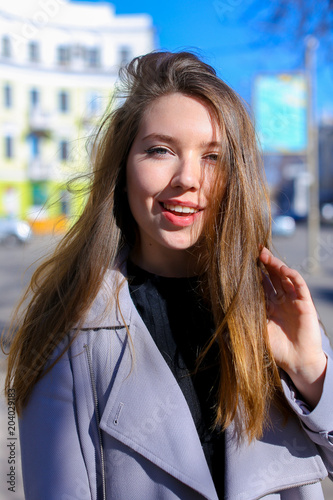 Close up beautiful young female person walking in good weather, buildings background. Concept of spring urban inspiration and beauty. photo
