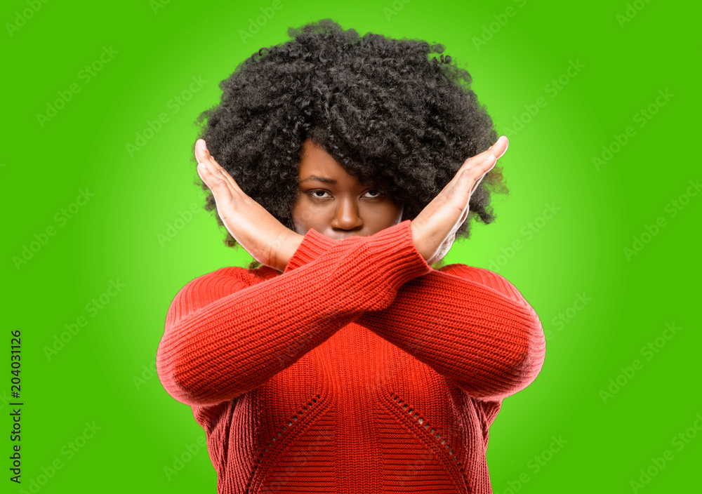Beautiful african woman annoyed with bad attitude making stop sign crossing hands, saying no, expressing security, defense or restriction Beautiful african woman annoyed with bad attitude making stop sign crossing hands, saying no, expressing security, defense or restriction