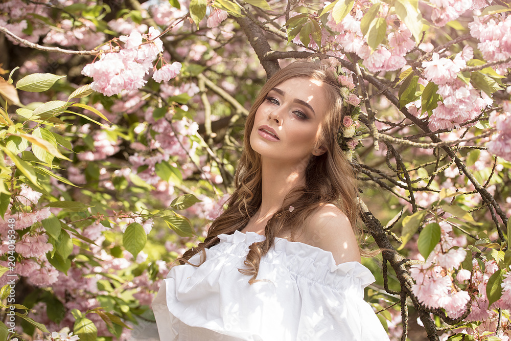 Fototapeta premium Attractive blonde girl in blooming garden.