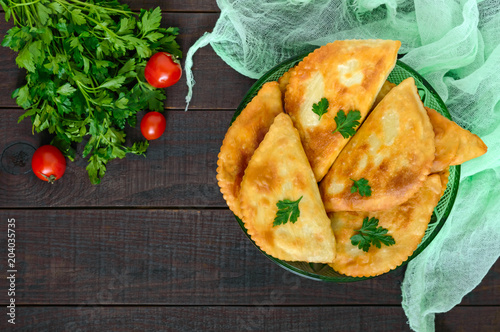 Juicy golden chebureks on a wooden table. Traditional Turkic-Mongolian dish. Street food. Bistro.