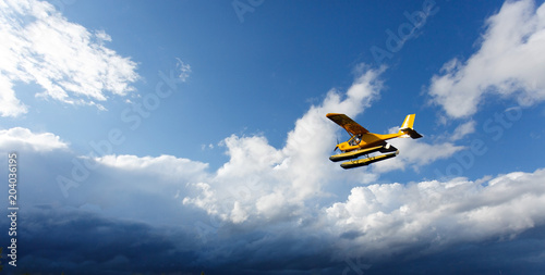 Tableau sur toile A small yellow hydroplane flying in sky