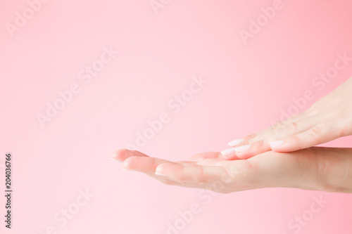 Beautiful  groomed woman s hand touching her perfect  smooth skin. Care about clean and soft hands skin. Beauty concept. Pink background.