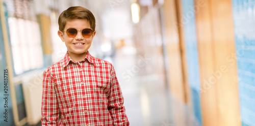 Handsome toddler child with green eyes confident and happy with a big crazy smile laughing at school corridor