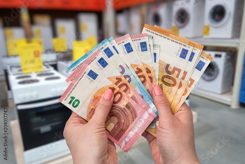 Female hands with euro banknotes in home appliances store, macro