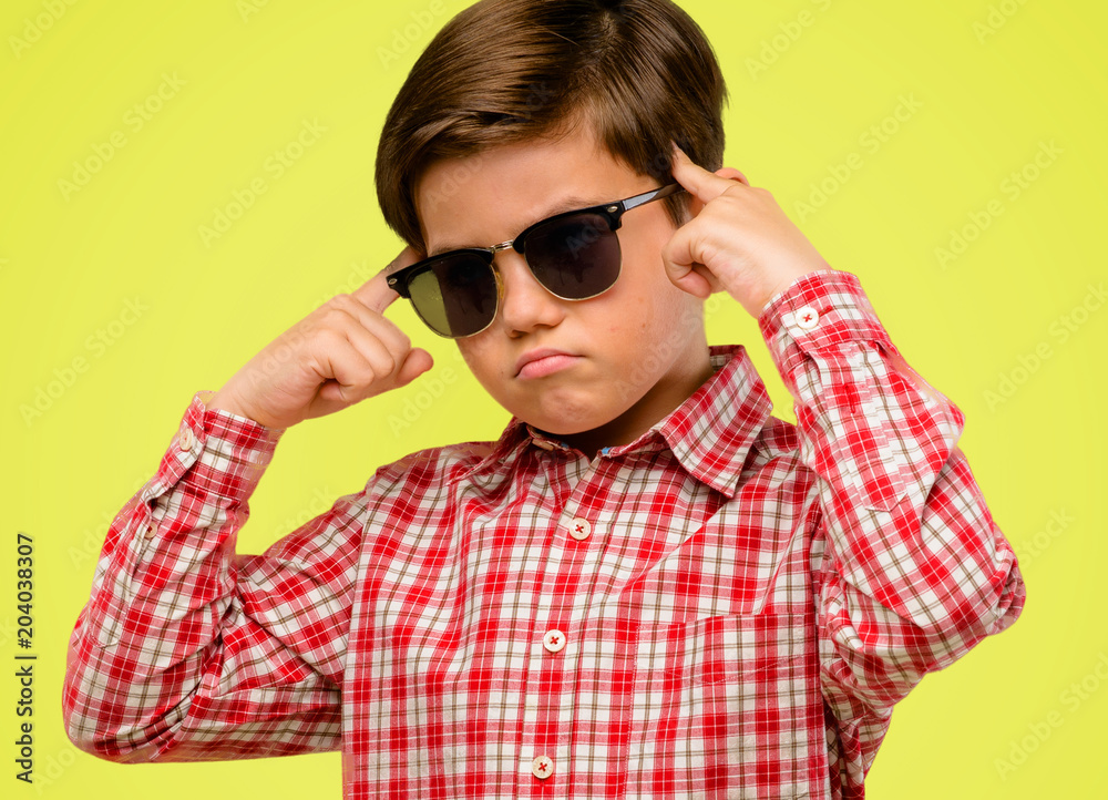 Handsome toddler child with green eyes doubt expression, confuse and wonder concept, uncertain future over yellow background Handsome toddler child with green eyes doubt expression, confuse and wonder concept, uncertain future over yellow background