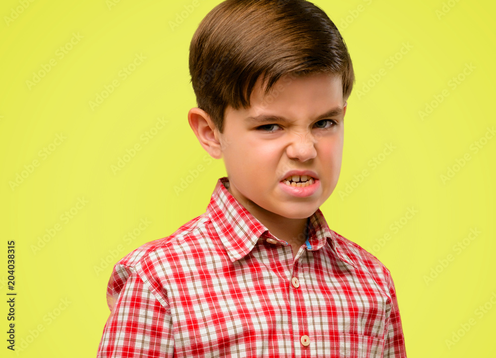 Handsome toddler child with green eyes angry and stressful frowns face in dissatisfaction, irritated and annoyed, expressing anger over yellow background Handsome toddler child with green eyes angry and stressful frowns face in dissatisfaction, irritated and annoyed, expressing anger over yellow background