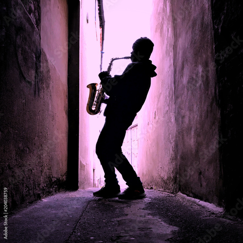 Saxophone player in silhouette with pink tinge