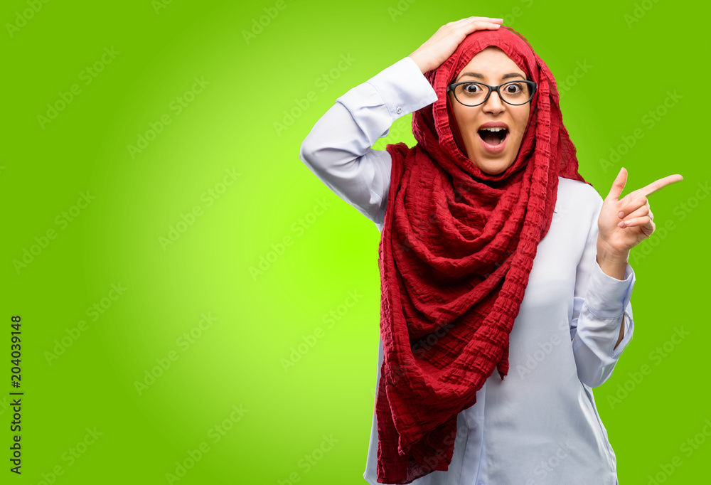 Young arab woman wearing hijab pointing away side with his finger Young arab woman wearing hijab pointing away side with his finger