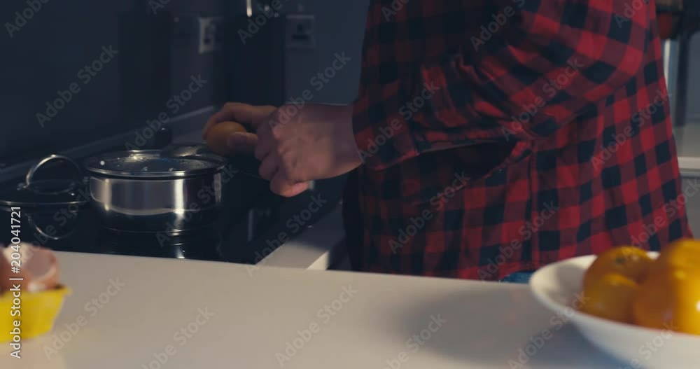 Young man poaching eggs at home Young man poaching eggs at home