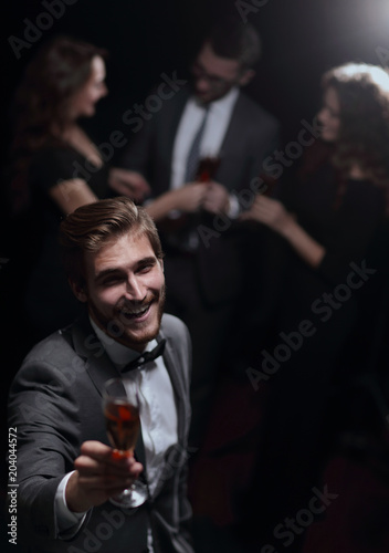 stylish young man standing with a glass of champagne.