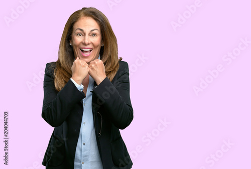 Middle age business woman happy and surprised cheering expressing wow gesture