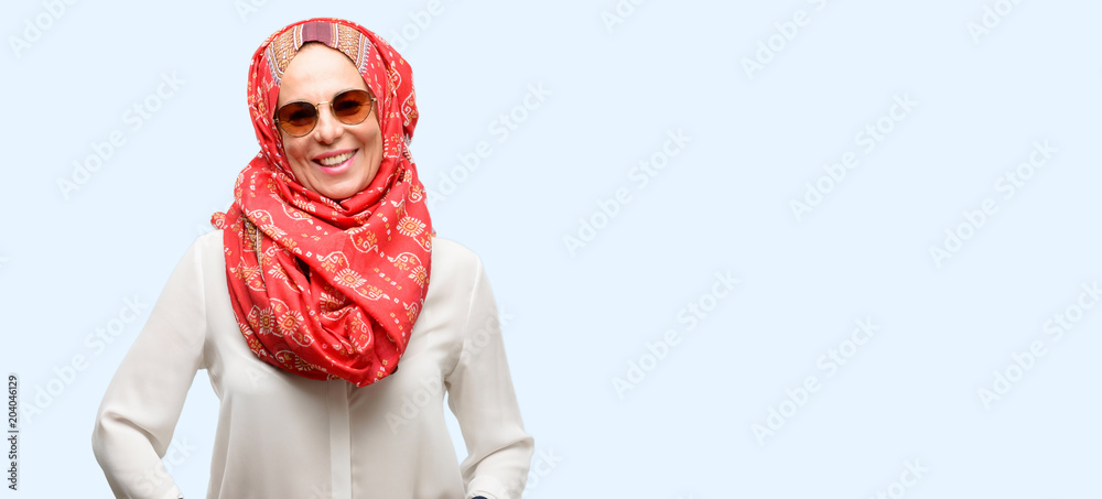 Middle age muslim arab woman wearing hijab confident and happy with a big natural smile laughing isolated blue background Middle age muslim arab woman wearing hijab confident and happy with a big natural smile laughing isolated blue background