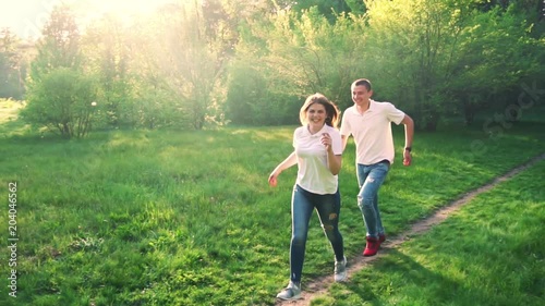 Happy young couple having fun in spring park. The guy runs after the girl
