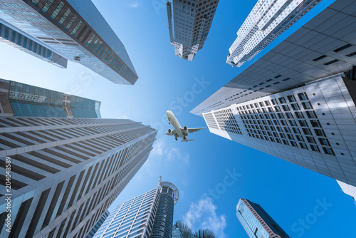 Photography Plane flying over city on blue sky background.