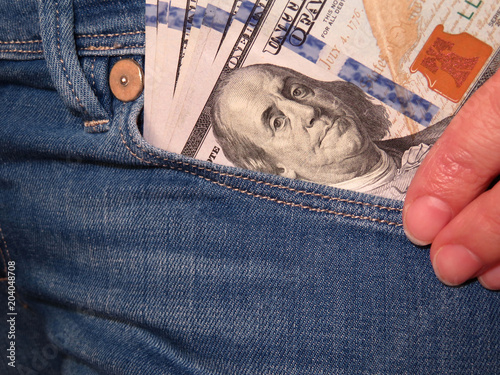 Woman with US dollars in the front pocket of jeans. Shopping or wages concept