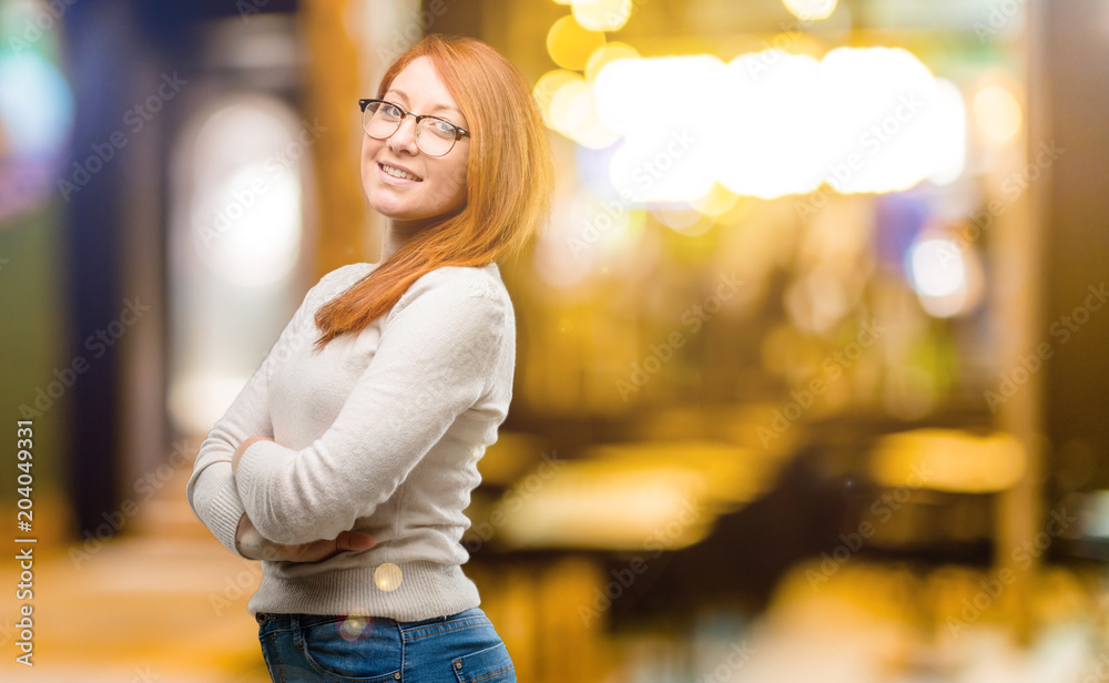 Beautiful young redhead woman with crossed arms confident and happy with a big natural smile laughing at night