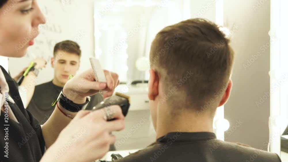 Haircutter making male hair cut with hair clipper and comb in hairdressing salon close up. Hairdresser doing professional hairstyle with electric shaver. Haircutter making male hair cut with hair clipper and comb in hairdressing salon close up. Hairdresser doing professional hairstyle with electric shaver.