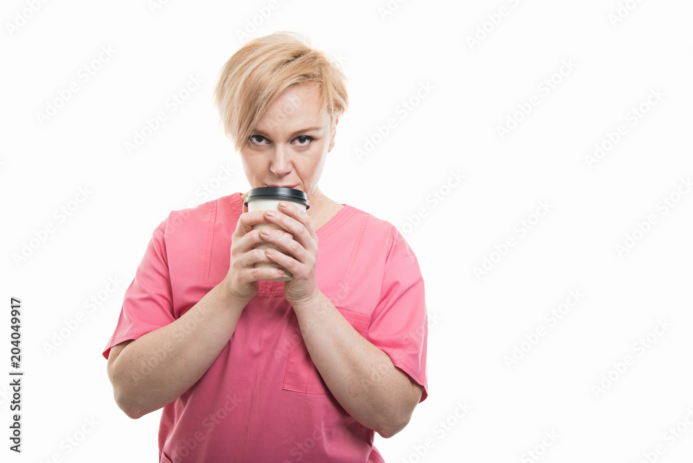 Attractive female nurse wearing pink scrubs holding takeaway coffee Attractive female nurse wearing pink scrubs holding takeaway coffee