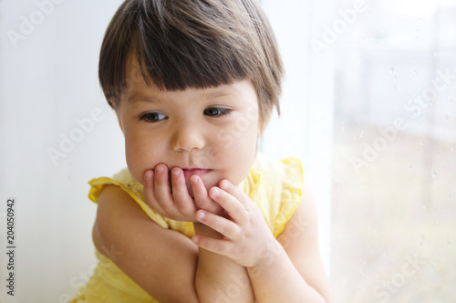 dreaming little girl portrait leans on elbows on window longing for something. happy smiling child thinking about pleasing thoughts photo