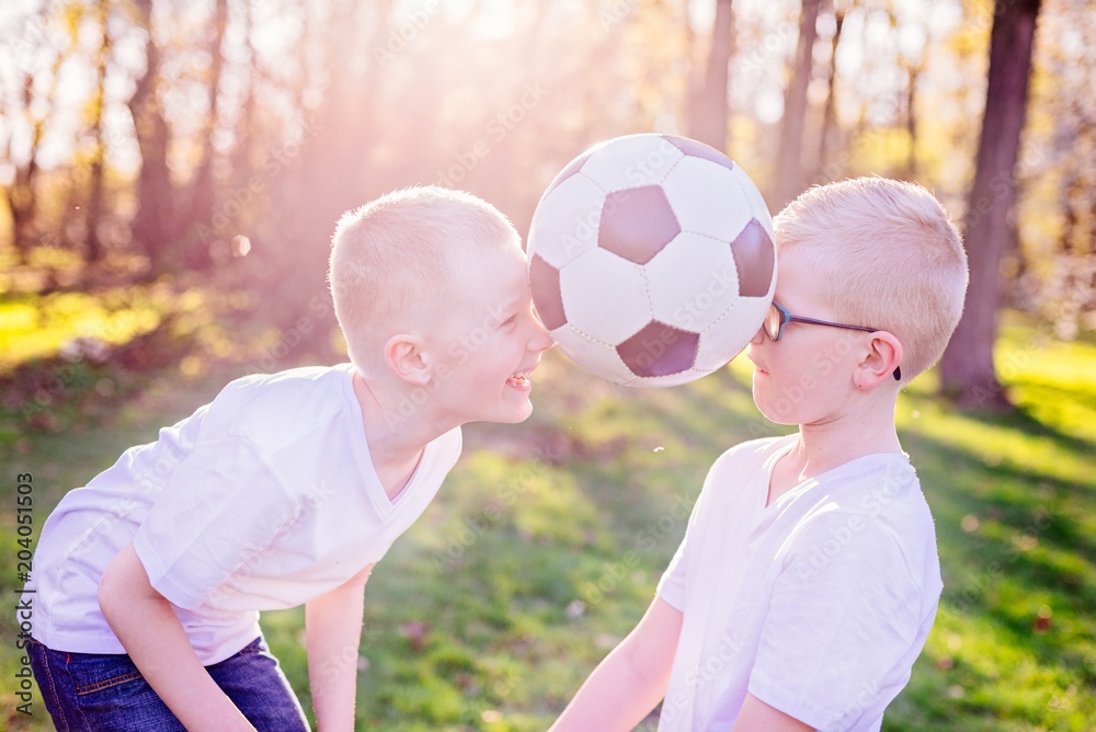 Obraz premium Boys brothers playing with ball on green grass in park.