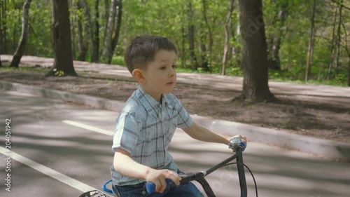 Little boy on a bicycle at asphalt road. Cute boy learning to ride bicycle on a bicycle track. photo