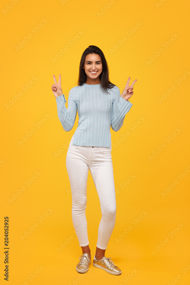 Stylish hipster woman on yellow backdrop