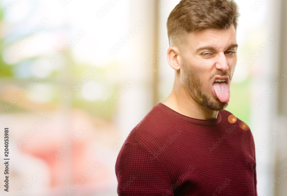 Handsome young man feeling disgusted with tongue out Handsome young man feeling disgusted with tongue out