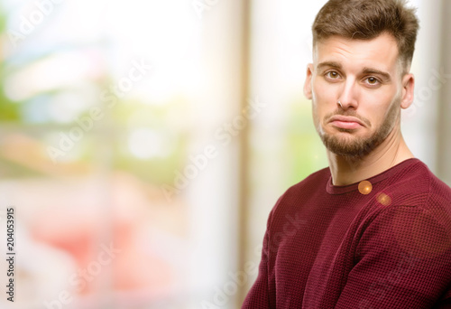 Handsome young man with sad and upset expression, unhappy