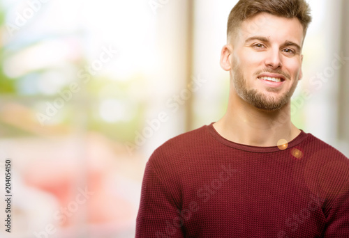 Handsome young man confident and happy with a big natural smile laughing, natural expression