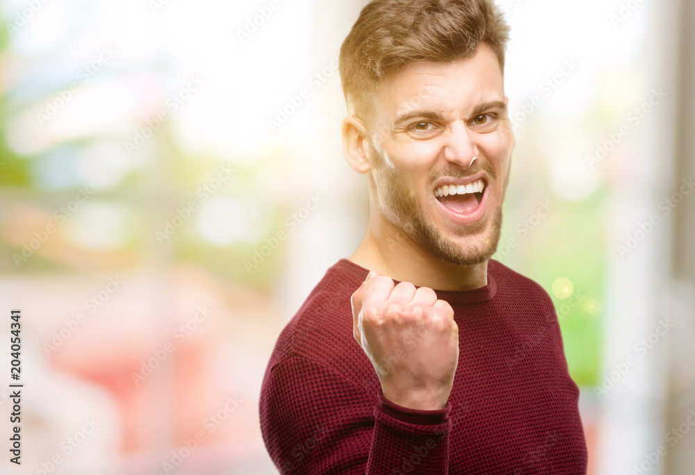 Handsome young man happy and excited expressing winning gesture. Successful and celebrating victory, triumphant