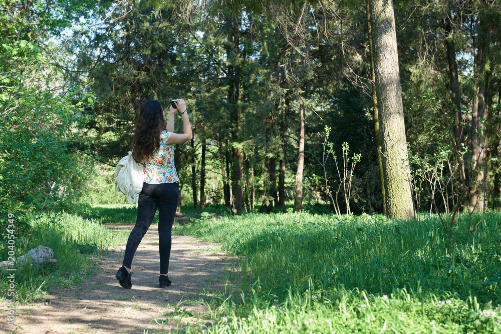 girl with camera taking pictures of nature in spring, beautiful forest and trees on a Sunny day