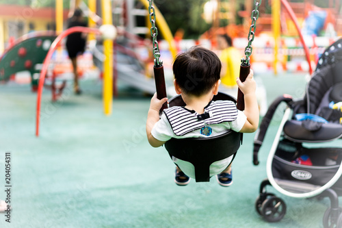 Tableau sur toile backview of little boy having fun on a swing